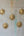 Cinq ex-voto KIFF KIFF en forme de cœur sacré en métal doré martelé disposés sur un mur en béton brut.