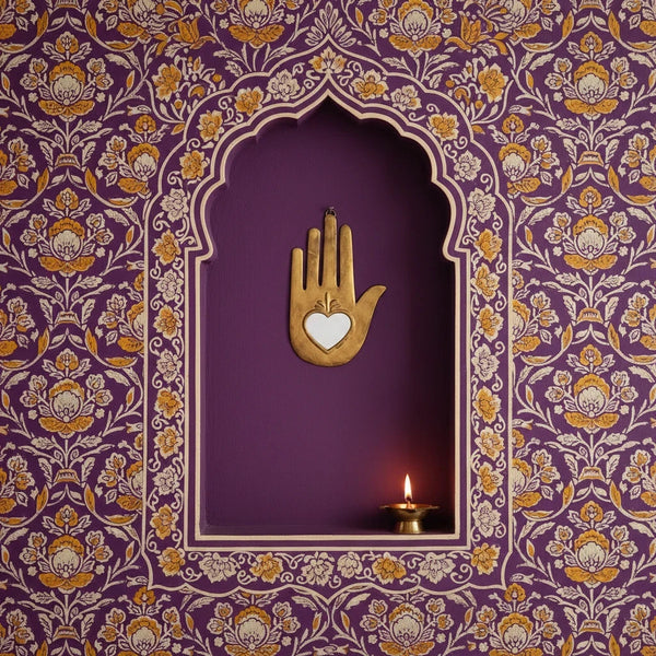 Ex-Voto Naïa KIFF KIFF en métal doré en forme de main stylisée avec un cœur, fixé dans une niche murale violette.
