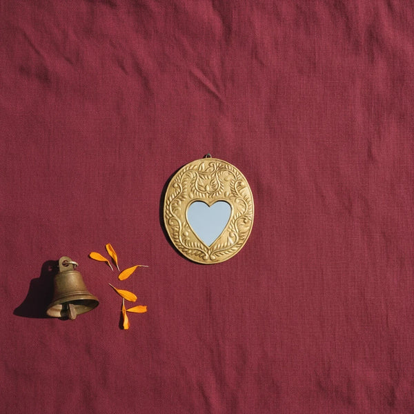 Ex-Voto Gemma KIFF KIFF en métal doré martelé de forme ovale avec un miroir central en forme de cœur sur fond rouge
