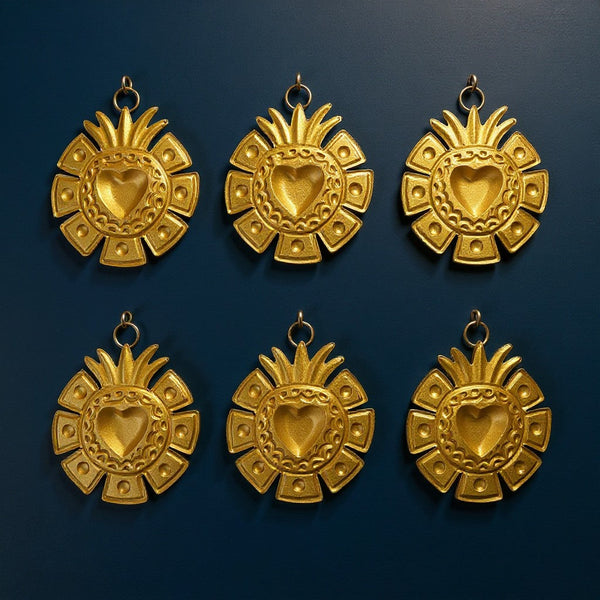 Six ex-voto Ray dorés de KIFF KIFF avec un design géométrique en forme de cœur sacré sur fond bleu foncé