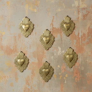 Five KIFF KIFF Freddy gold metal heart ex-voto wall decorations with LOVE inscription on a textured rustic wall