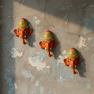 Trois masques muraux KIFF KIFF représentant Ganesh Vinayaka en papier mâché rouge peint à la main sur un mur texturé