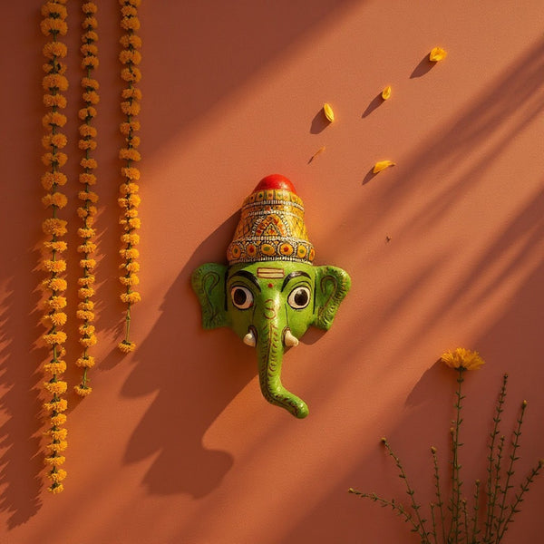 Masque mural Ganesh Vinayaka vert en papier mâché artisanal KIFF KIFF sur fond terracotta avec guirlandes de fleurs