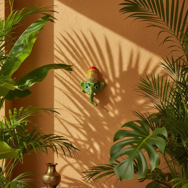 Masque mural KIFF KIFF Ganesh Vinayaka vert en papier mâché peint à la main, suspendu sur un mur ocre avec des plantes