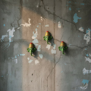 Trois masques muraux KIFF KIFF Ganesh Vinayaka verts en papier mâché artisanal sur un mur en béton texturé