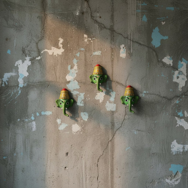Trois masques muraux KIFF KIFF Ganesh Vinayaka verts en papier mâché artisanal sur un mur en béton texturé