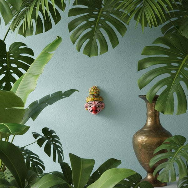 Masque mural Garuda KIFF KIFF en papier mâché peint à la main, 10 cm, entouré de plantes tropicales et d'un vase.