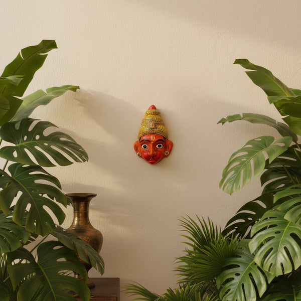 Masque mural Hanuman orange en papier mâché KIFF KIFF, pièce artisanale indienne peinte à la main sur un mur beige.