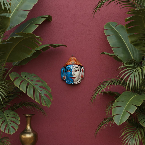 Masque mural artisanal KIFF KIFF Hari Hara en papier mâché, représentant Vishnou et Shiva sur un mur rouge.