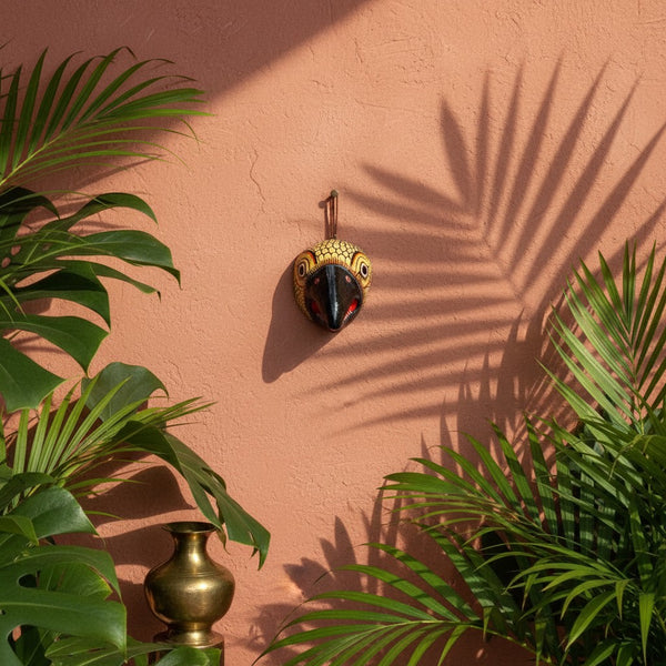 Masque mural KIFF KIFF Jatayu en papier mâché jaune moutarde avec bec noir, suspendu sur un mur terracotta décoré