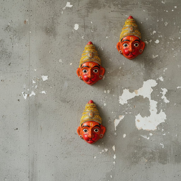 Trois masques muraux KIFF KIFF représentant Hanuman en papier mâché orange peint à la main sur un mur en béton