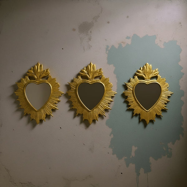 Trois miroirs ex-voto KIFF KIFF Clyde dorés en forme de cœur avec des pointes asymétriques sur un mur texturé.