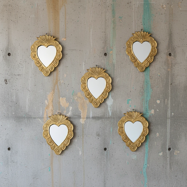 Composition murale de cinq miroirs ex-voto KIFF KIFF en métal doré martelé en forme de cœur sur un mur en béton