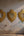Trois miroirs ex-voto dorés Bonnie de KIFF KIFF en forme de cœur avec des détails cannelés sur un mur texturé.
