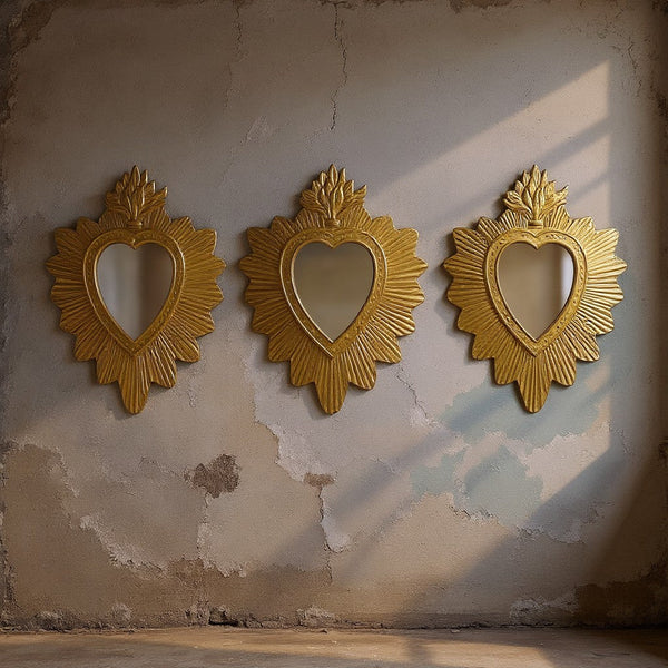 Trois miroirs ex-voto dorés Bonnie de KIFF KIFF en forme de cœur avec des détails cannelés sur un mur texturé.