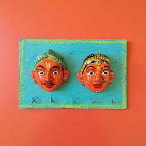 Patère murale artisanale KIFF KIFF avec deux masques de couple hindou peints à la main sur une plaque en bois bleue