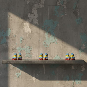 Trois paires de pieds de Lakshmi KIFF KIFF en papier mâché bleu, posées sur une étagère devant un mur texturé.