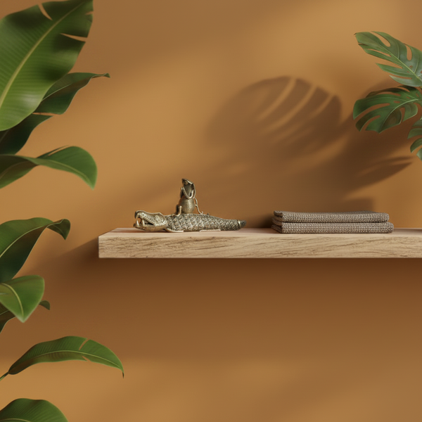 Statuette crocodile en laiton KIFF KIFF posée sur une étagère en bois avec des plantes vertes en arrière-plan