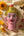 Statuette KIFF KIFF en papier mâché rose représentant un visage hindou peint à la main sur un tissu crème avec fleurs