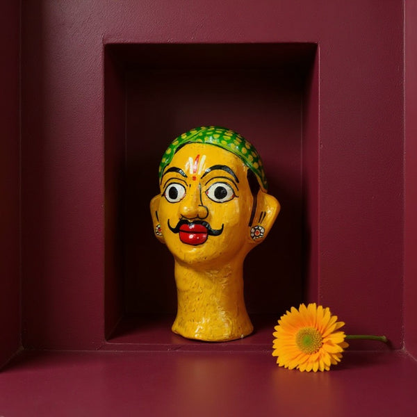 Statuette KIFF KIFF de visage d'homme hindou en papier mâché peint à la main, posée sur un fond bordeaux.