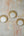 Three KIFF KIFF Zoya circular mirrors with decorative gold metal frames mounted on a textured rustic wall.