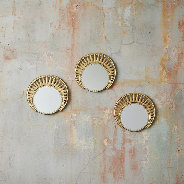 Three KIFF KIFF Zoya circular mirrors with decorative gold metal frames mounted on a textured rustic wall.